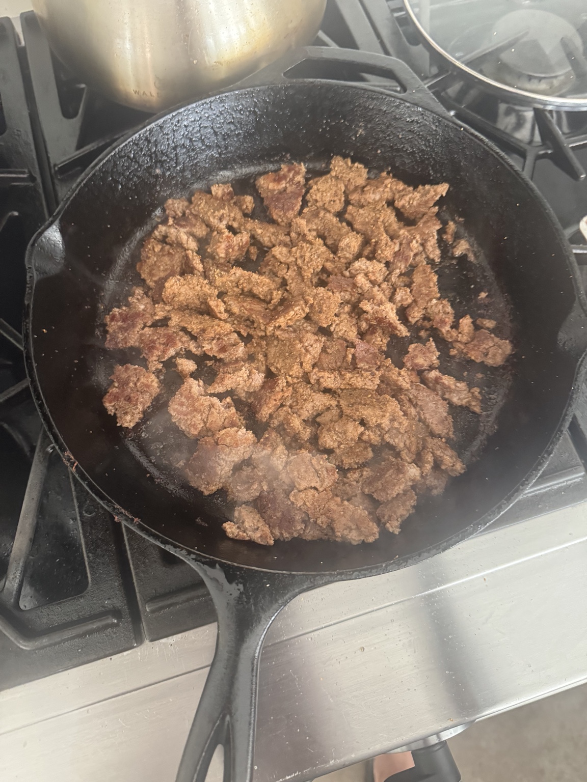 Ground beef browning in a cast-iron skillet