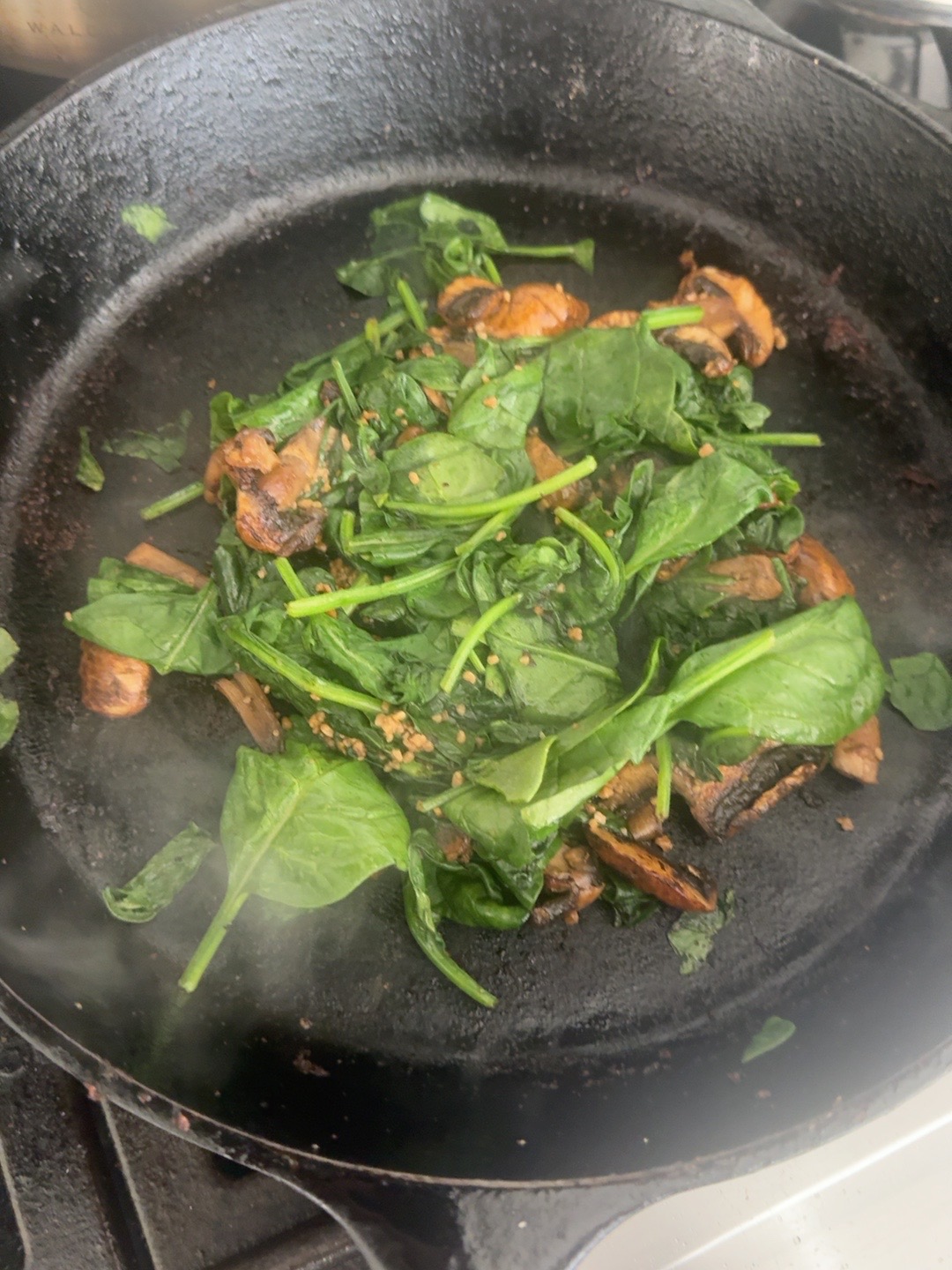 Spinach, mushrooms and minced garlic cooking together in the skillet