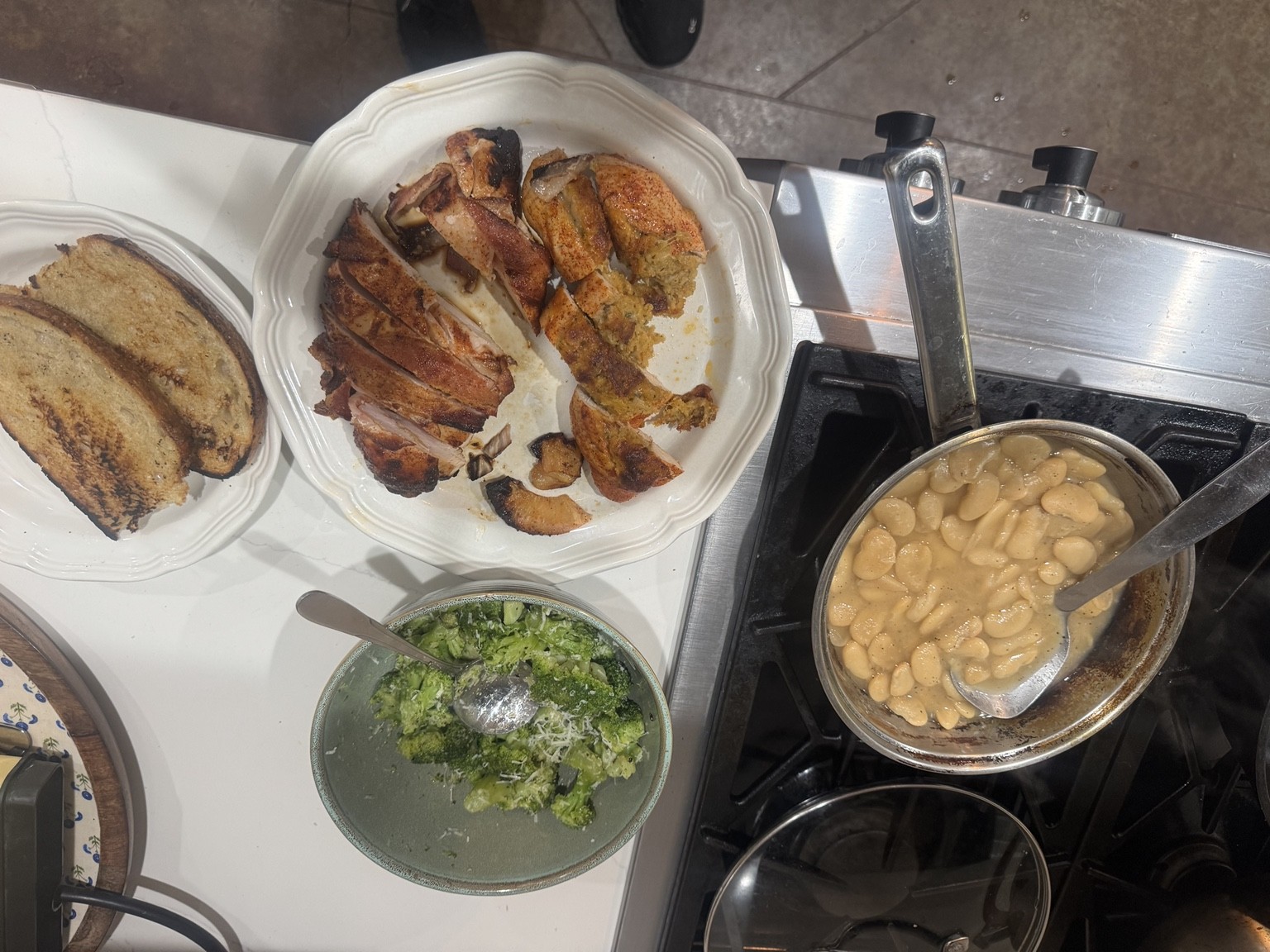 Sliced crab-stuffed chicken and pineapple-stuffed chicken thighs beside broccoli, toasted bread and a pan of butter beans